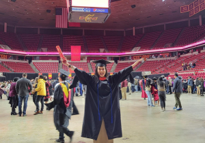 Me posing infront of a stadium wearing graduation gown